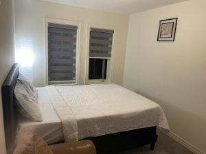 1 dormitorio con 1 cama y 2 ventanas en Comfort Queen, en Oshawa