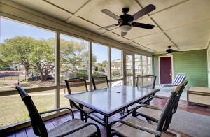 a table and chairs on a screened porch with a ceiling fan at 3C Mariners Walk by AvantStay Beach Pool Access Enclosed Porch in Isle of Palms