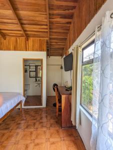 a room with a bed and a desk and a window at El Nido Lodge in Monteverde Costa Rica