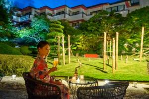 una mujer sentada en una mesa con una copa de vino en Kinugawa Grand Hotel Yumenotoki, en Nikko