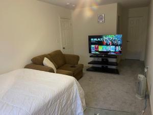 1 dormitorio con 1 cama, TV y sofá en Comfort Queen, en Oshawa