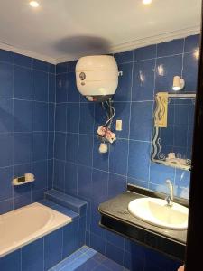 uma casa de banho em azulejos azuis com uma banheira e um lavatório em شقه مصيفيه شاطى الفردوس البيطاش em Alexandria