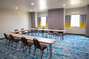 Microtel Inn & Suites by Wyndham Searcy في سيرسي: مجموعة طاولات وكراسي في غرفة ذات ستائر صفراء