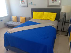 niebieskie łóżko z żółtymi poduszkami i kanapą w obiekcie Villamar2 w mieście Yeguada