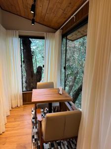 jadalnia ze stołem i krzesłami oraz dużym oknem w obiekcie Estalagem Serra de Minas em Monte Verde w mieście Monte Verde