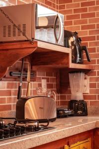 a kitchen with a counter with a microwave and a stove at Casa NR 2 Hospedaria in Tiradentes