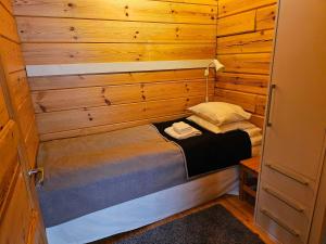 een kleine kamer met een bed in een houten hut bij Luppoloma in Saariselkä