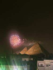 una pantalla de fuegos artificiales delante de las pirámides por la noche en Zahira Pyramids View en El Cairo
