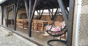 a porch with a hammock and wooden tables and chairs at Nika's House Trosobna kuća sa trpezarijom i kuhinjom,u skopu jos dva apartmana,bazen,terasa i sauna in Palić
