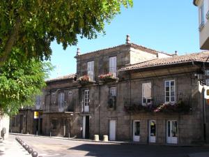 - un vieux bâtiment en pierre avec des fleurs aux fenêtres dans l'établissement Casa Grande De Trives, à A Pobra de Trives