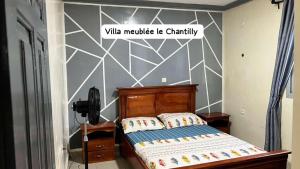 ein Schlafzimmer mit einem Bett mit einer weißen und grauen Wand in der Unterkunft Dany Chantilly in Jaunde