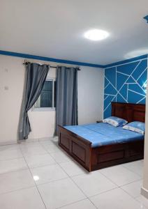 1 dormitorio con 1 cama con cabecero azul en Dany Chantilly en Yaundé
