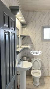 ein Badezimmer mit einem weißen WC und einem Waschbecken in der Unterkunft Dany Chantilly in Jaunde