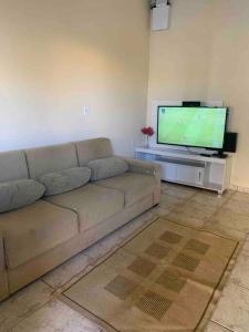 uma sala de estar com um sofá e uma televisão de ecrã plano em Casa de Férias 1purbana em Ribeirão Preto
