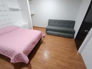 a bedroom with a pink bed and a couch at Loft Santa rosa in Apizaco