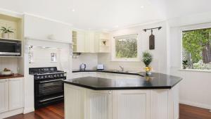 a kitchen with white cabinets and a black counter top at Southrose Cottage in Moss Vale