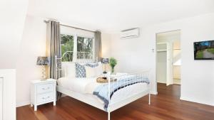 a white bedroom with a bed and a window at Southrose Cottage in Moss Vale