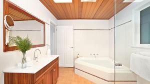a bathroom with a tub and a sink and a mirror at Southrose Cottage in Moss Vale