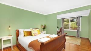 a bedroom with a bed with green walls and a window at Southrose Cottage in Moss Vale +16 photos