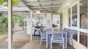 eine abgeschirmte Veranda mit einem Tisch und Stühlen darauf in der Unterkunft Southrose Cottage in Moss Vale