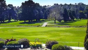 - une vue sur un parcours de golf avec de l'herbe verte et des arbres dans l'établissement Southrose Cottage, à Moss Vale