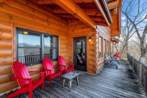 une cabine avec des chaises rouges sur une terrasse couverte en bois dans l'établissement Spacious Cabin With Fantastic Long Range Mountain and Lake Views - Lake Lure - The Overlook cabin, à Lake Lure