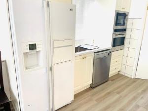 a white kitchen with a refrigerator and a sink at House in Thomastown in Melbourne