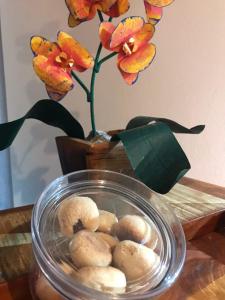 a glass bowl with doughnuts in front of a vase with flowers at Suítes Encanto de Minas in Tiradentes