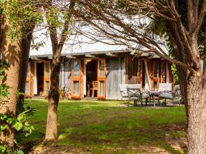 a house with two chairs and trees in the yard at The Gatehouse - Takaka Holiday Home in Takaka
