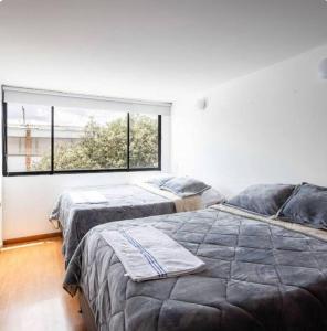 two beds in a room with a large window at Enorme Casa Campestre en Bogotá in Bogotá