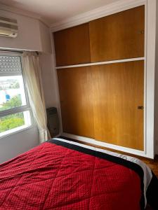 a bedroom with a red bed and a large wooden closet at Departamento En San Martin in San Martín