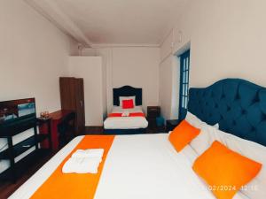 a bedroom with a large bed with orange and white pillows at PARDOS HOUSE INN in Cusco