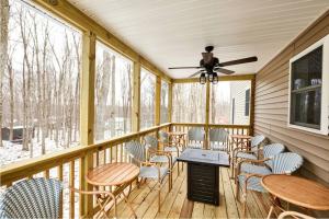 eine Veranda mit Stühlen, Tischen und einem Deckenventilator in der Unterkunft Casa di Montagna/5BR/3Bath/NearResorts/PetsAllowed in Pocono Lake