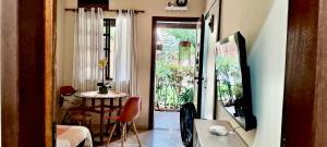 a living room with a table and a door to a room at Iguaba Grande, 3 minutos do mar in Iguaba Grande