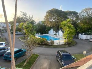 a parking lot with cars parked in front of a pool at Beach Life Villa in Bridgetown