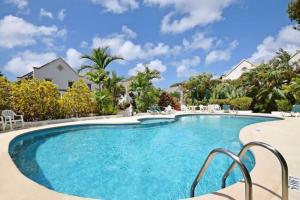 una piscina en un complejo con sillas y árboles en Beach Life Villa, en Bridgetown