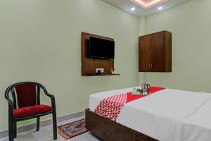 a bedroom with a bed and a chair and a tv at OYO Flagship 70105 Hotel Pulick Awadh in Lucknow