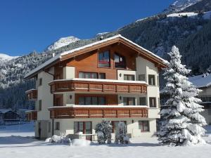 a large building in the snow in front of a mountain at Ferienhaus Antigua in Saas-Grund