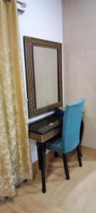 a mirror sitting on top of a piano with a blue chair at Hotel Versa Appartment Gulberg in Lahore