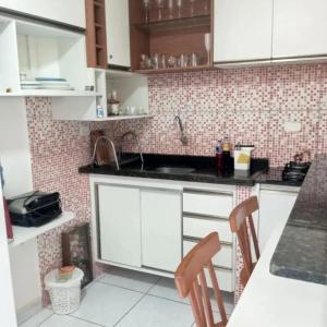 a kitchen with white cabinets and a black counter top at Residencial Jardins Ilha de Itamaracá in Vila Velha