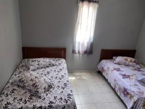 2 Betten in einem kleinen Zimmer mit Fenster in der Unterkunft Casa tchitchi in São Filipe