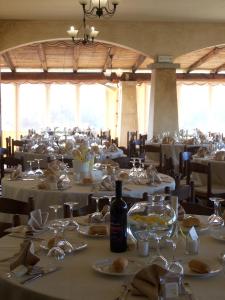 Hotel Ristorante Funtana Abbas في سانت أنطونيو دي غالورا: غرفة طعام مع طاولات مع مفارش المائدة البيضاء وزجاجات النبيذ