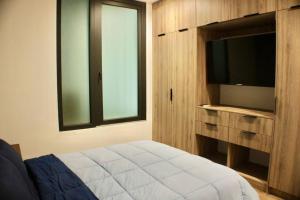 Un dormitorio con una cama y un televisor y una ventana. en Brujas Tower- Hermoso departamento a pie de playa., en La Florida