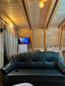 a black leather couch in a room with wooden ceilings at Woodland Cottage in Plav