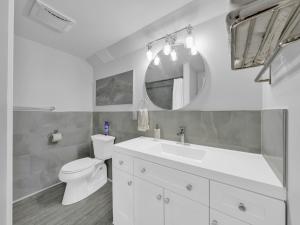 a white bathroom with a toilet and a mirror at Cliffside Suite #3 - Seacliff Beach Suites in Leamington +25 photos