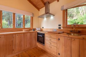 eine Küche mit Holzschränken, einem Waschbecken und Fenstern in der Unterkunft Mumfords in Akaroa