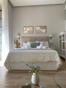 1 dormitorio con 1 cama grande y un jarrón de flores en Aljara Suites en Ronda