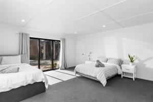 1 dormitorio blanco con 2 camas y ventana en Countryside Guest House, en Tamahere