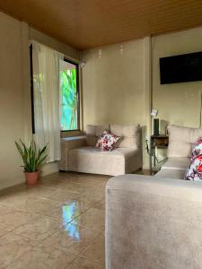 a living room with two couches and a window at Casa Heliconia in Puerto Jiménez