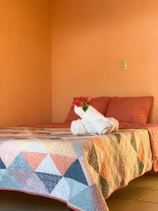 a bed with a quilt and a vase of flowers on it at Casa Heliconia in Puerto Jiménez